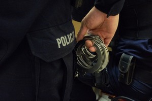 zdjęcie przedstawia: policjanta trzymającego w ręce kajdanki